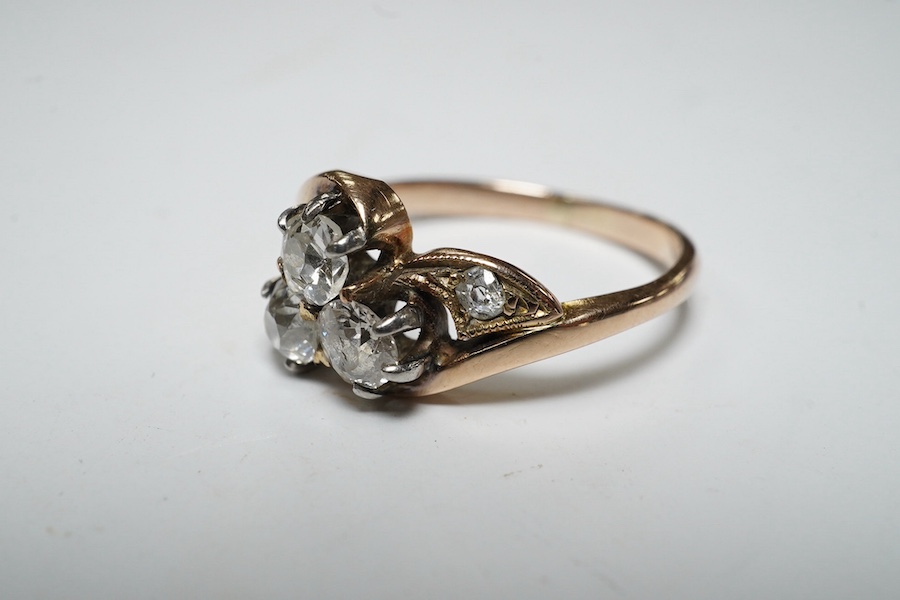 A yellow metal and three stone diamond set crossover ring, with single stone diamond set shoulder, size K, gross weight 2.4 grams. Condition - poor to fair